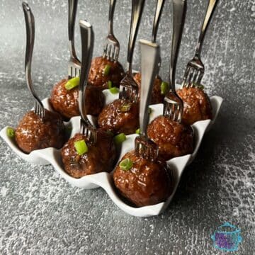 honey bourbon slow cooker meatballs on a tray on mini forks