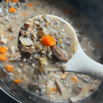 slow cooker mushroom and wild rice soup on a spoon over crockpot