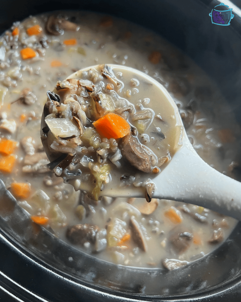 slow cooker mushroom and wild rice soup on a spoon over crockpot