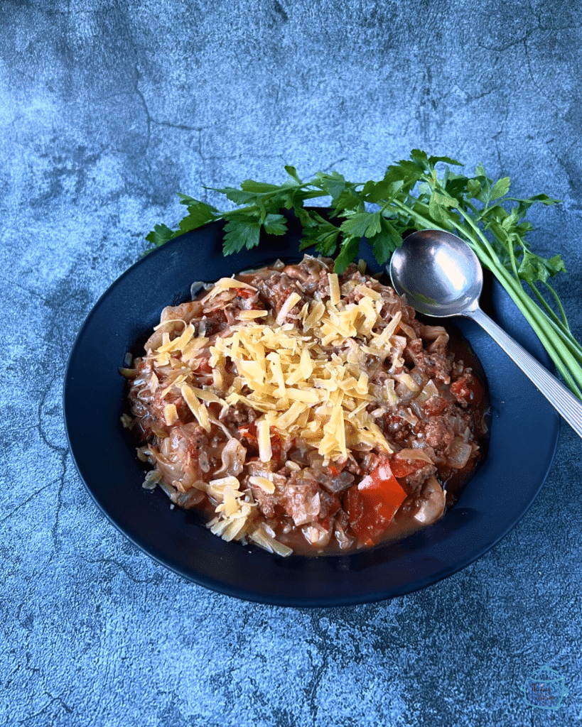 crockpot beef, cabbage and cheese in a black bowl with a spoon