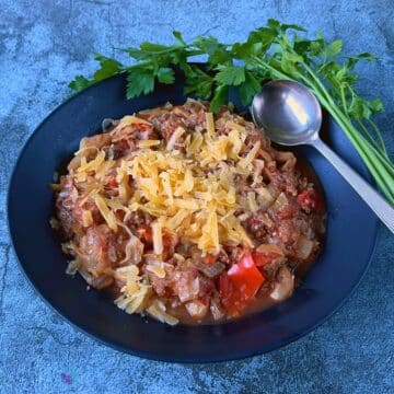 crockpot beef, cabbage and cheese in a black bowl with a spoon