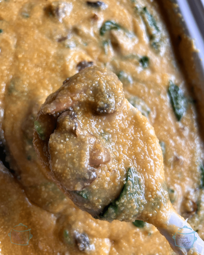 spinach and mushroom polenta on a spoon held over a crockpot