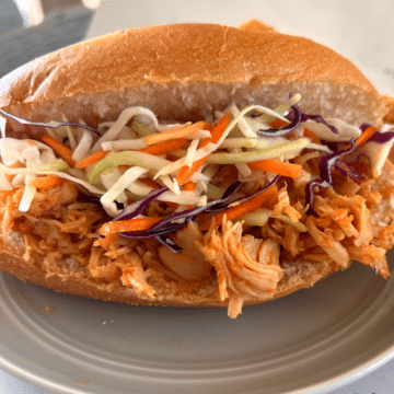 a sandwich made of slow cooker honey sriracha chicken and cabbage slaw