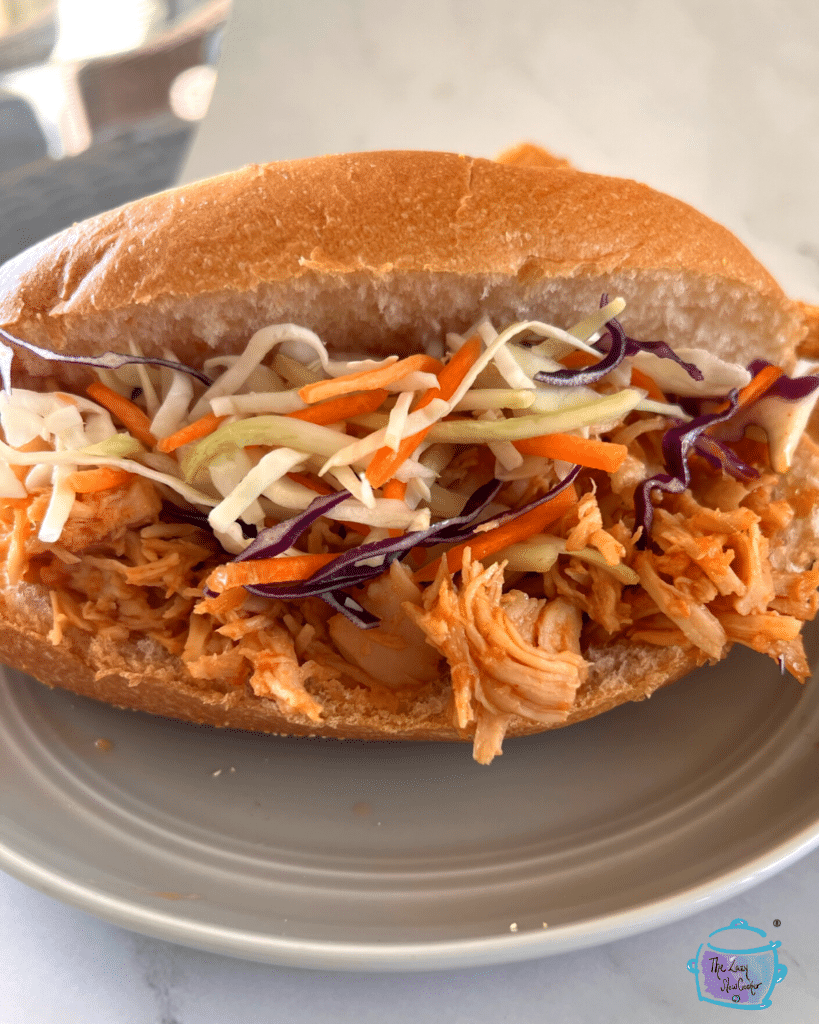 a sandwich made of slow cooker honey sriracha chicken and cabbage slaw