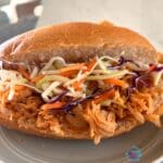 a sandwich made of slow cooker honey sriracha chicken and cabbage slaw