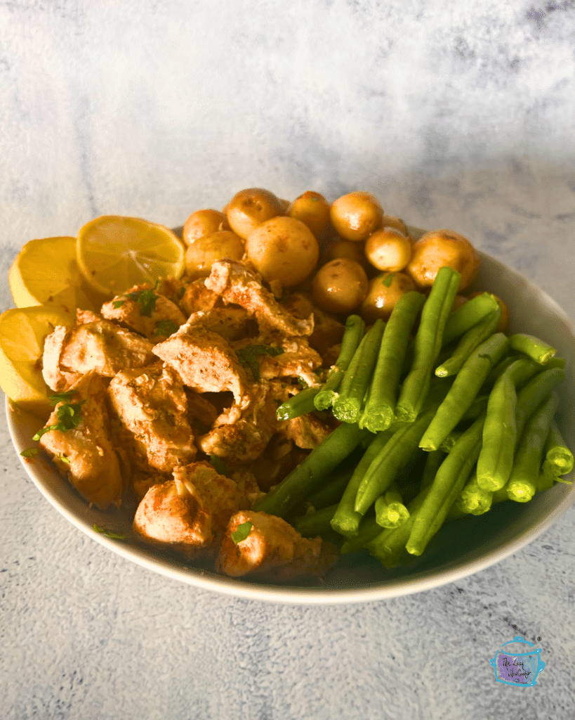 a large round bowl with lemon garlic butter slow cooker chicken, green beans and potatoes