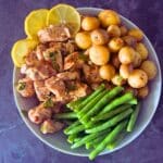 a large round bowl with lemon garlic butter slow cooker chicken, green beans and potatoes