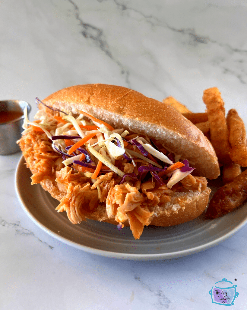 a sandwich made of slow cooker honey sriracha chicken and cabbage slaw