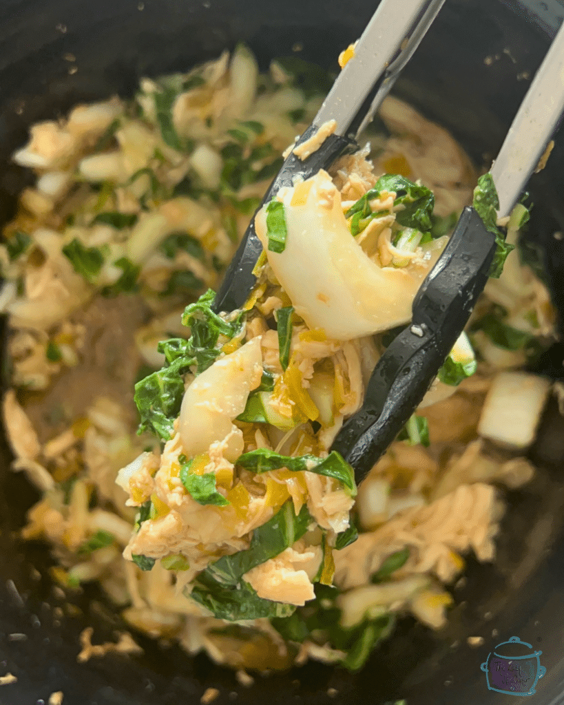chicken and bok choy held with tongs over a slow cooker