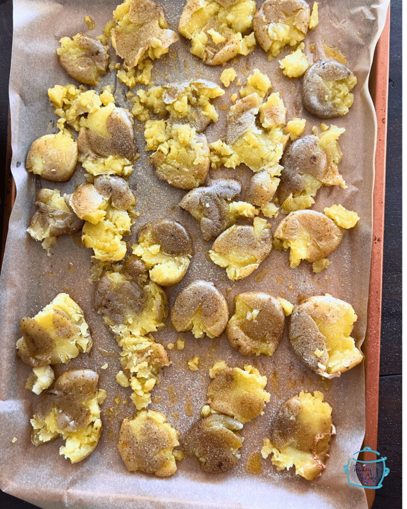 smashed potatoes uncooked on parchment paper with seasoning