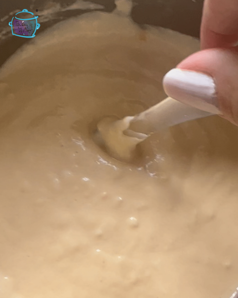 cheese dip in slow cooker being stirred with a spatula