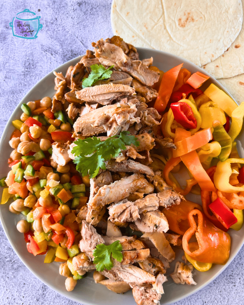 crockpot tequila lime sliced chicken on a plate with colorful pepper rings and a chopped salad. 