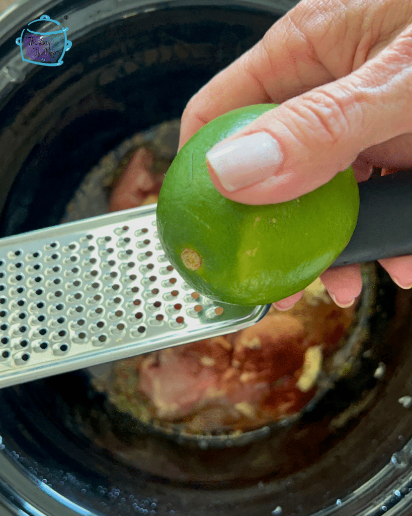 Lime and a zester held over a crock pot.