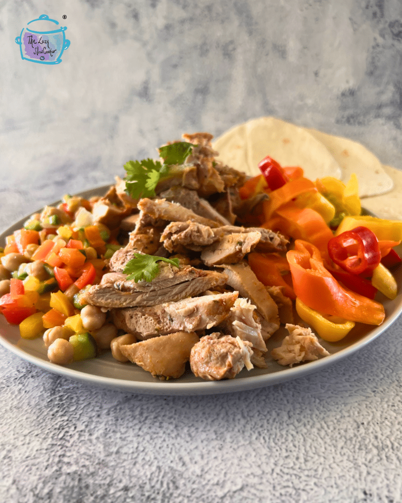 crockpot tequila lime sliced chicken on a plate with colorful pepper rings and a chopped salad.