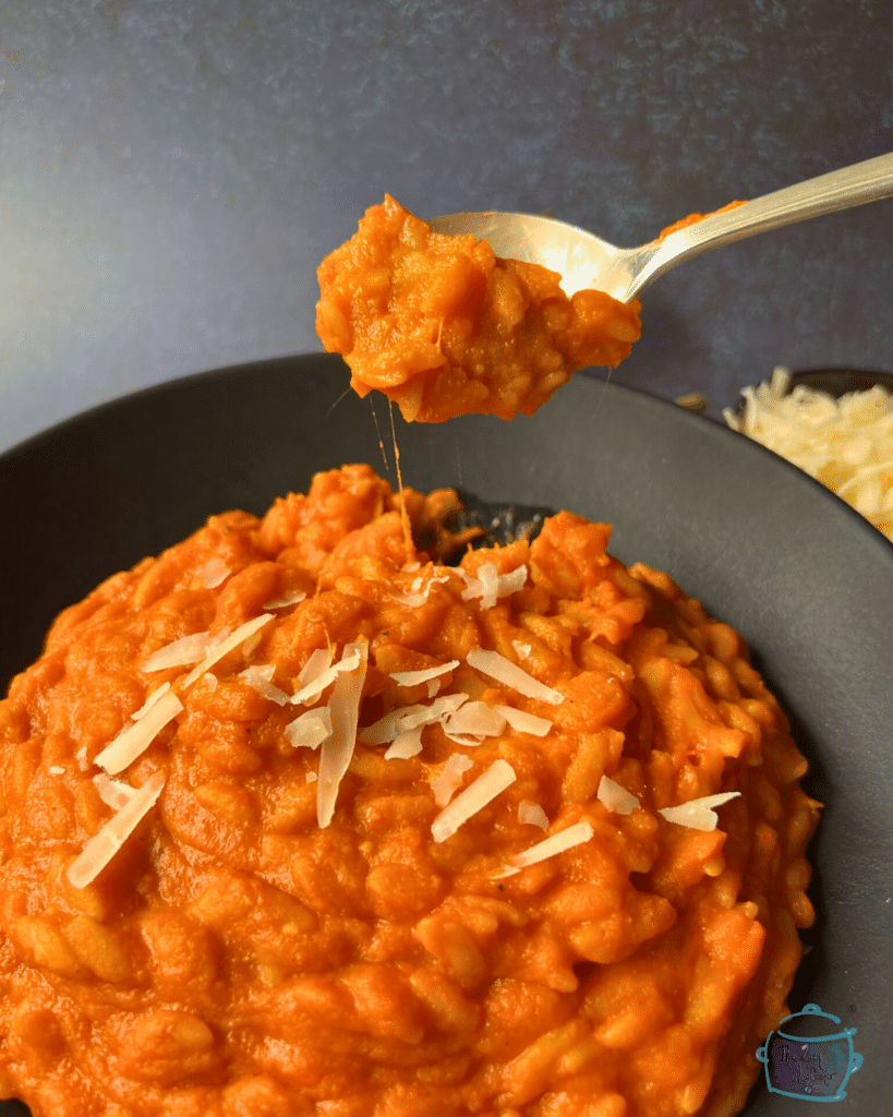 slow cooker vegetable sauce with orzo on a spoon over a black bowl