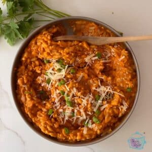 slow cooker vegetable sauce with orzo in a silver bowl topped with shredded parmesan cheese.