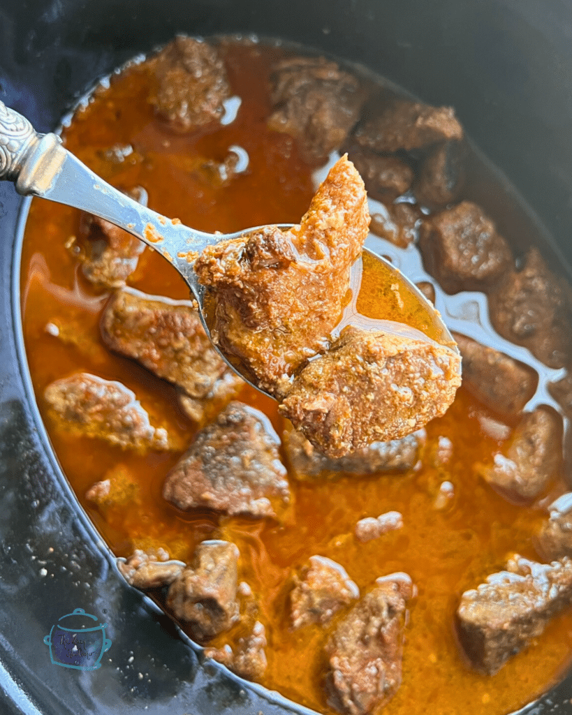 Cajun steak bites on a spoon over a slow cooker