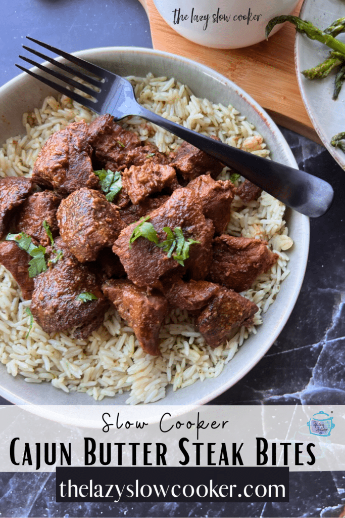 Slow cooked chunks of beef on a bed a rice with tomatoes and asparagus in the background