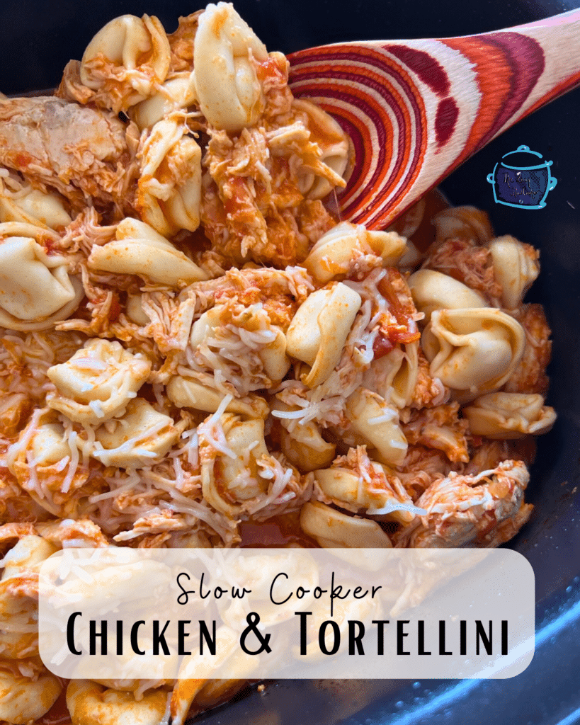 Shredded chicken and tortellini in a slow cooker with a wooden spoon.