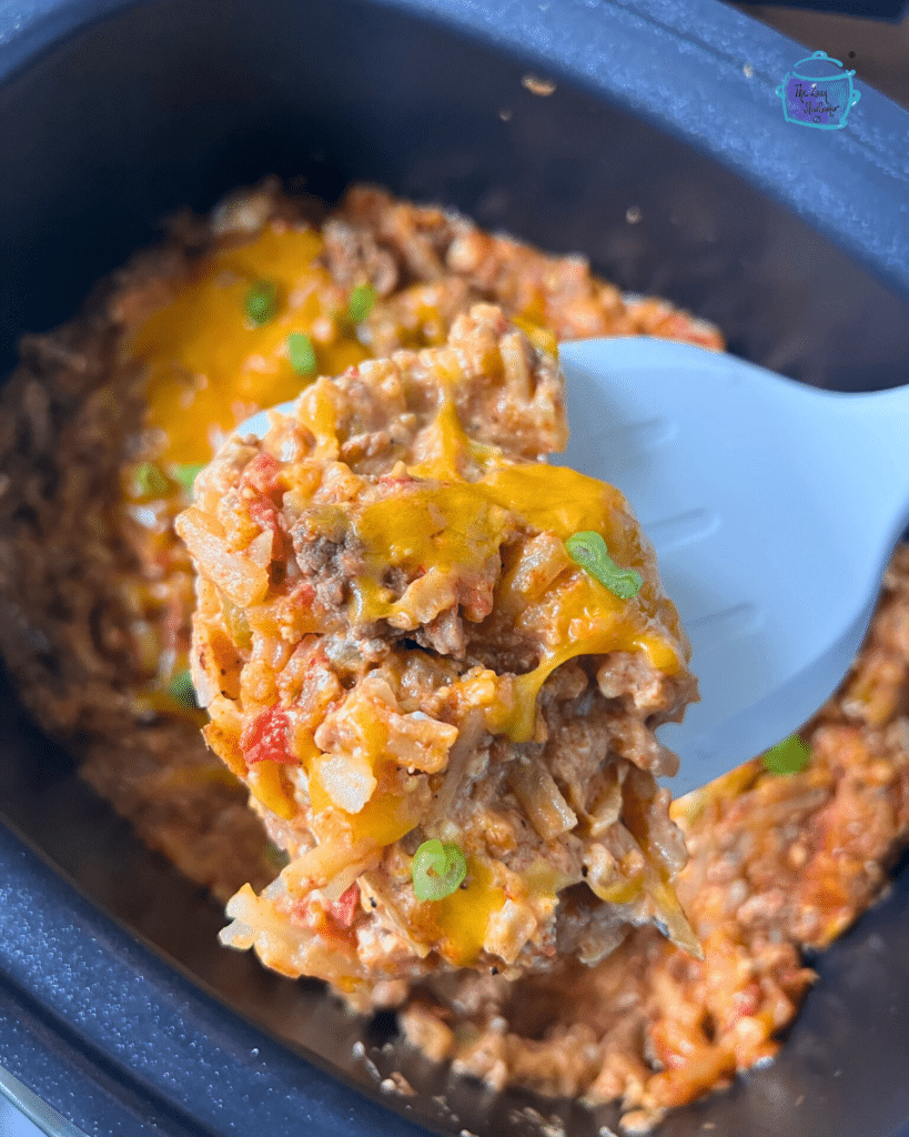 taco potato casserole on a spatula held over the crockpot it was cooked in