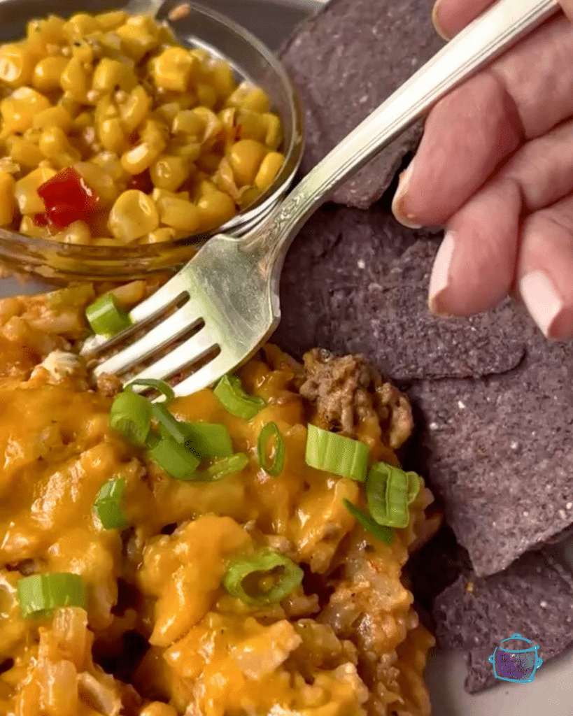 taco potato casserole on a plate with chips, corn and a fork