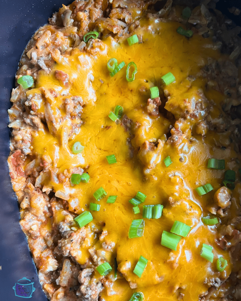taco casserole topped with melted cheese and sliced green onion still in slow cooker it was cooked in