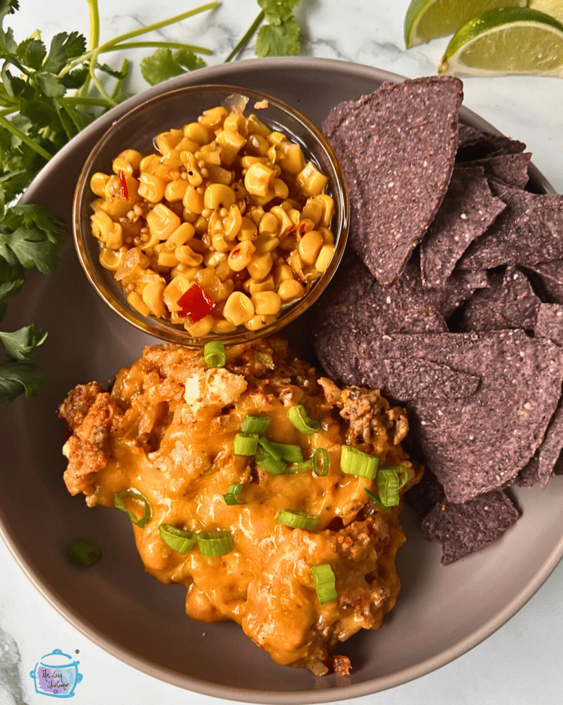 taco potato casserole on a plate with chips, corn.