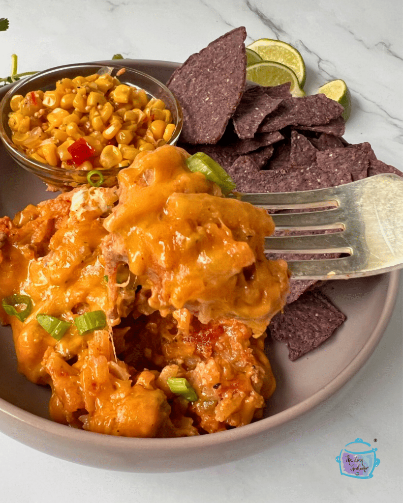 taco potato casserole on a plate with chips, corn and a fork