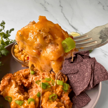 taco potato casserole on a plate with chips, corn and a fork