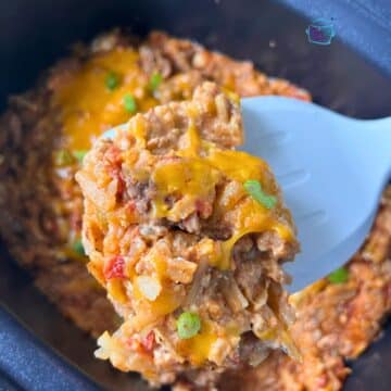taco potato casserole on a spatula held over the crockpot it was cooked in