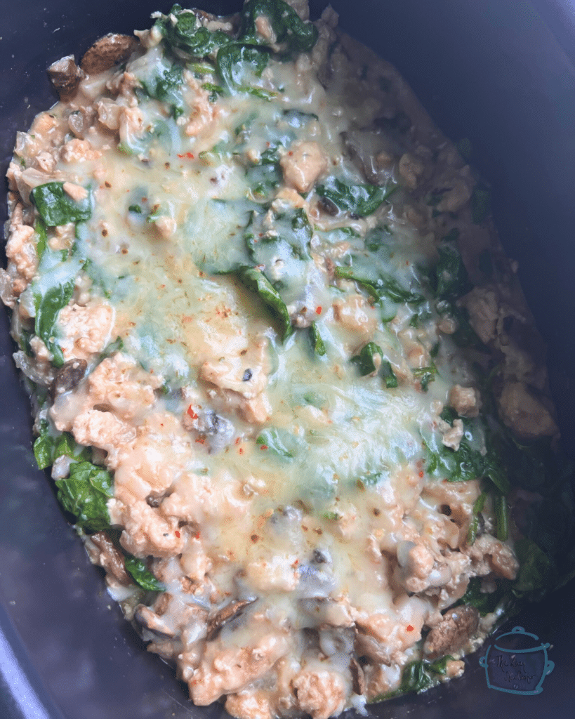 Turkey and spinach casserole in a slow cooker topped with cheese