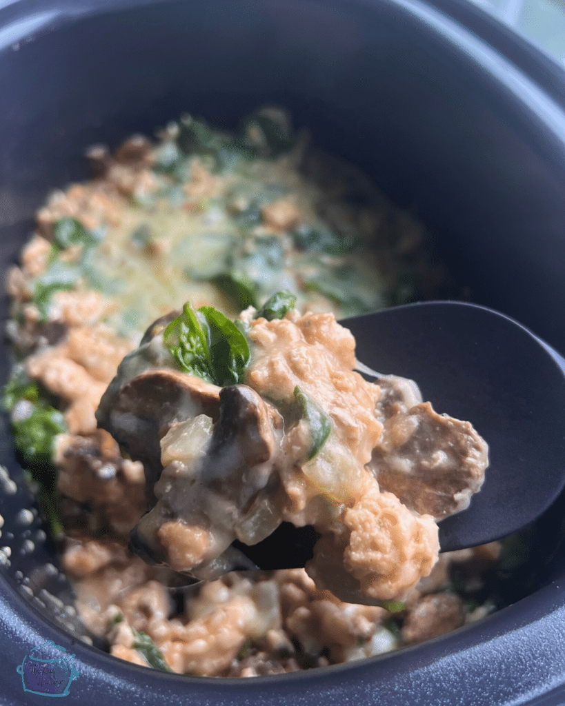 Turkey and spinach casserole in a slow cooker topped with cheese