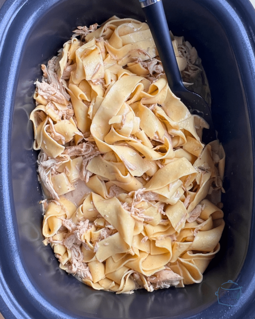 Cooked chicken in a crock pot with pasta.