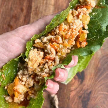 Slow cooker ground turkey in a lettuce leaf held in a hand.