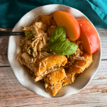 balsamic peach slow cooker chicken in a white bowl with a fork