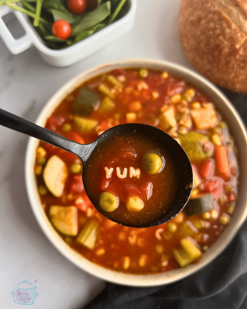 a bowl of alphabet soup with a spoonful of the same. the noodles in the spoon spell the word YUM.