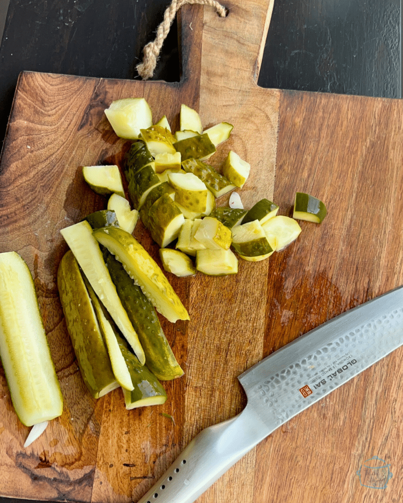chopped pickles on a cutting board with a knife