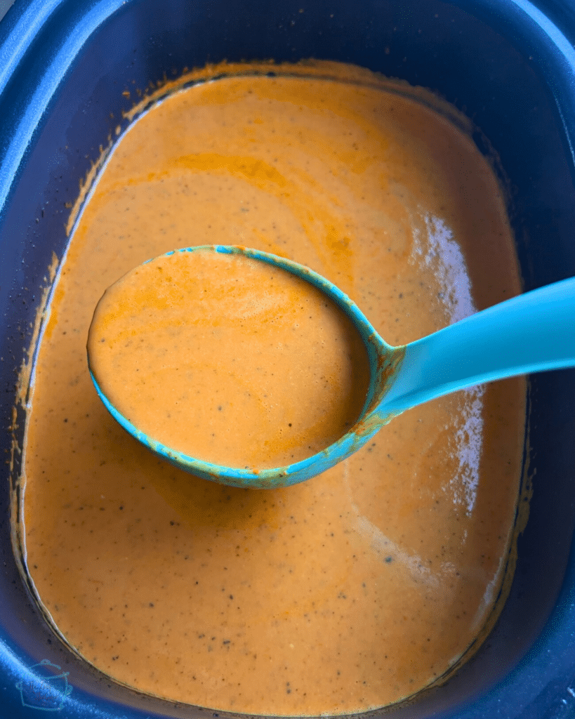 tomato and feta soup ingredients in a crockpot after cooking and blending with a ladleful of the same