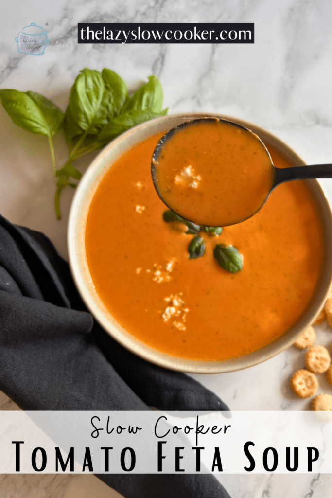 A spoonful of tomato and feta cheese soup held over a bowlful of the same with crackers off to the side.