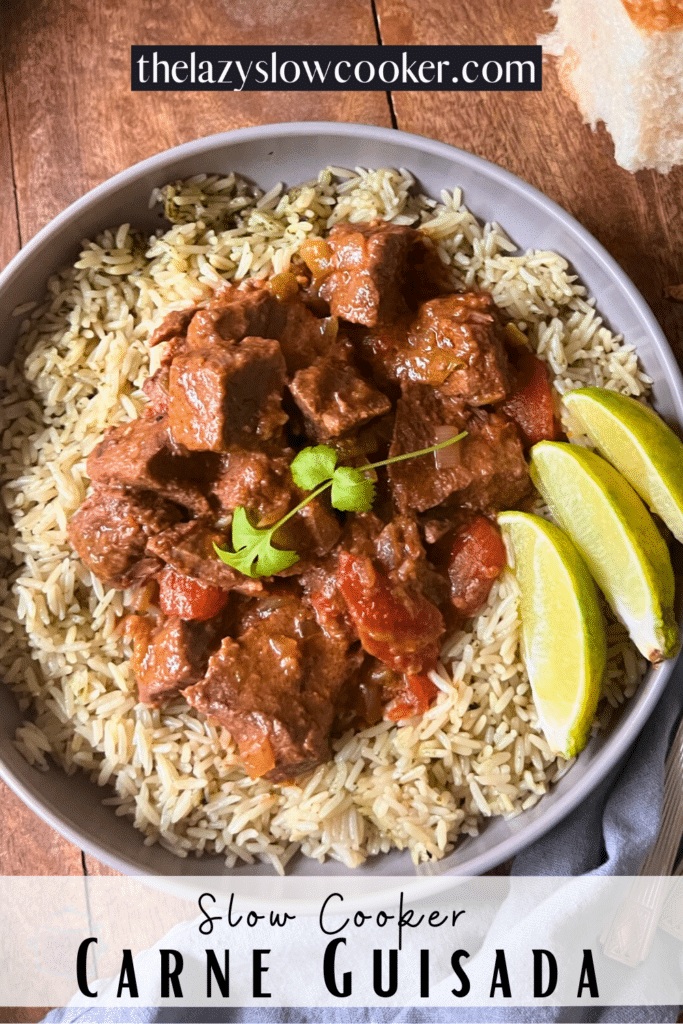 Mexican beef stew on a bed of rice in a grey bowl with lime wedges on the side