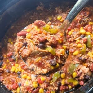 a ladle full of cooked leftover turkey chili held over a crockpot full of the same