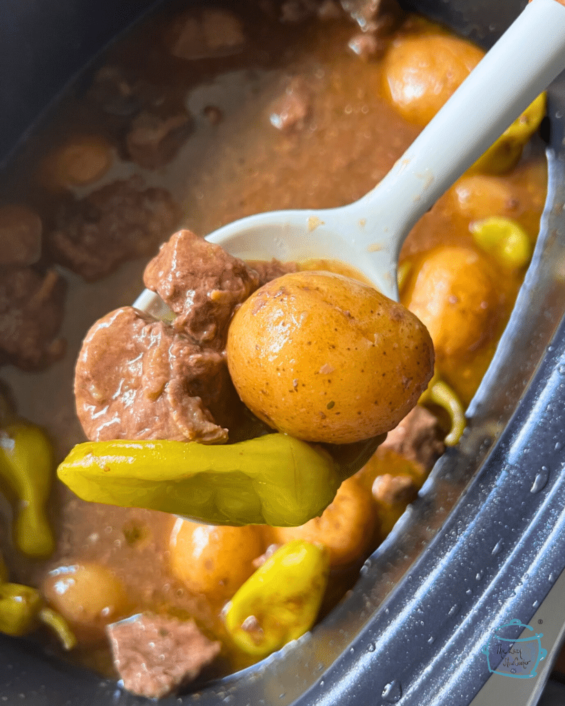 Mississippi beef stew on a spoon over a slow cooker