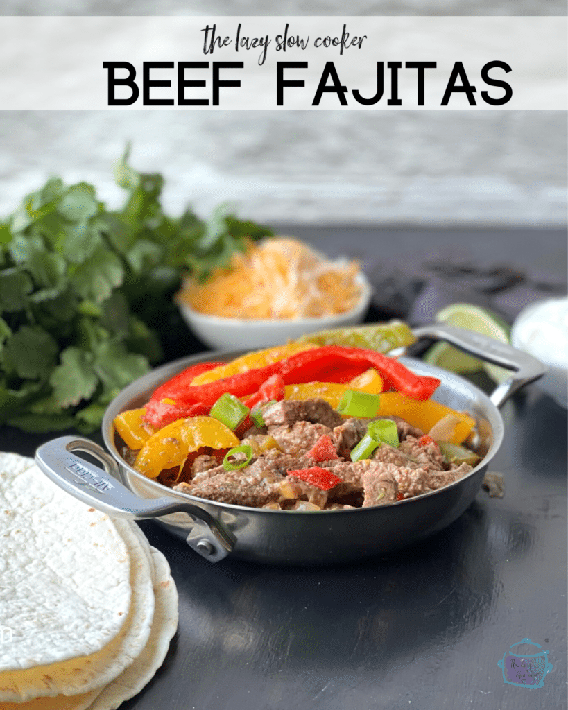 strips of beef and peppers in fajita sauce on a silver serving dish with handles and tortillas off to the side