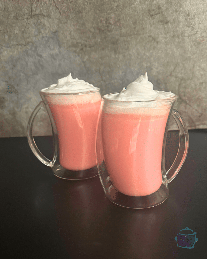 two mugs of slow cooker strawberry hot chocolate topped with whipped cream