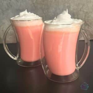 two mugs of slow cooker strawberry hot chocolate topped with whipped cream