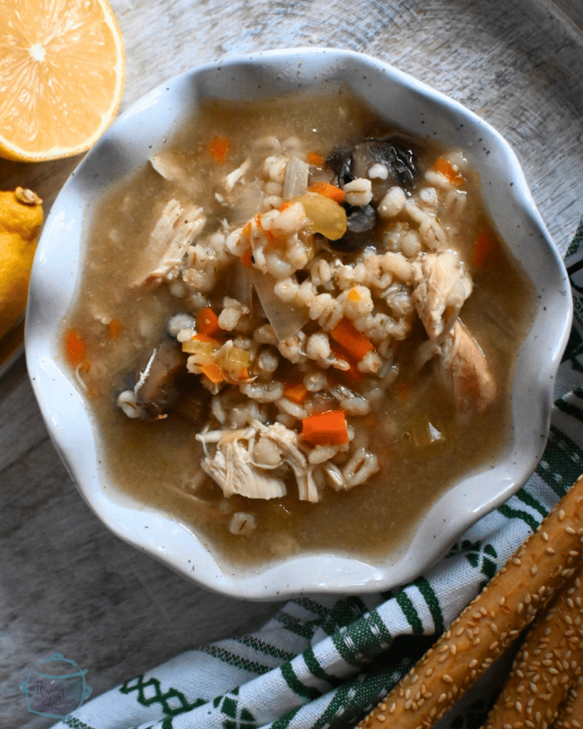 a white bowl filled with soup, mushrooms, veggies and barley