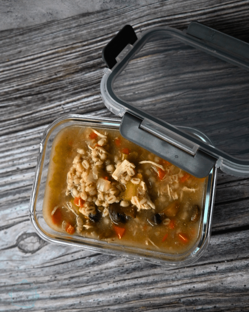 a reusable container filled with soup with a lid on the side ready to be stored in the fridge or freezer
