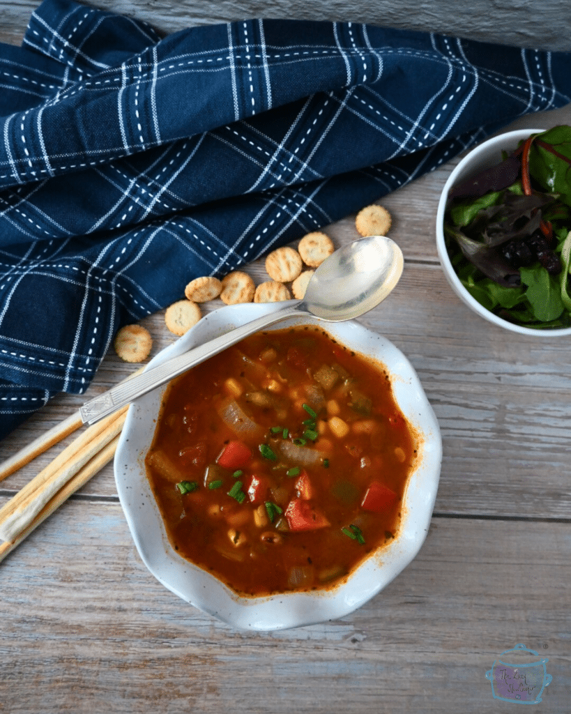 A bowl of slow cooker cowboy soup with a spoon and crackers off to the side