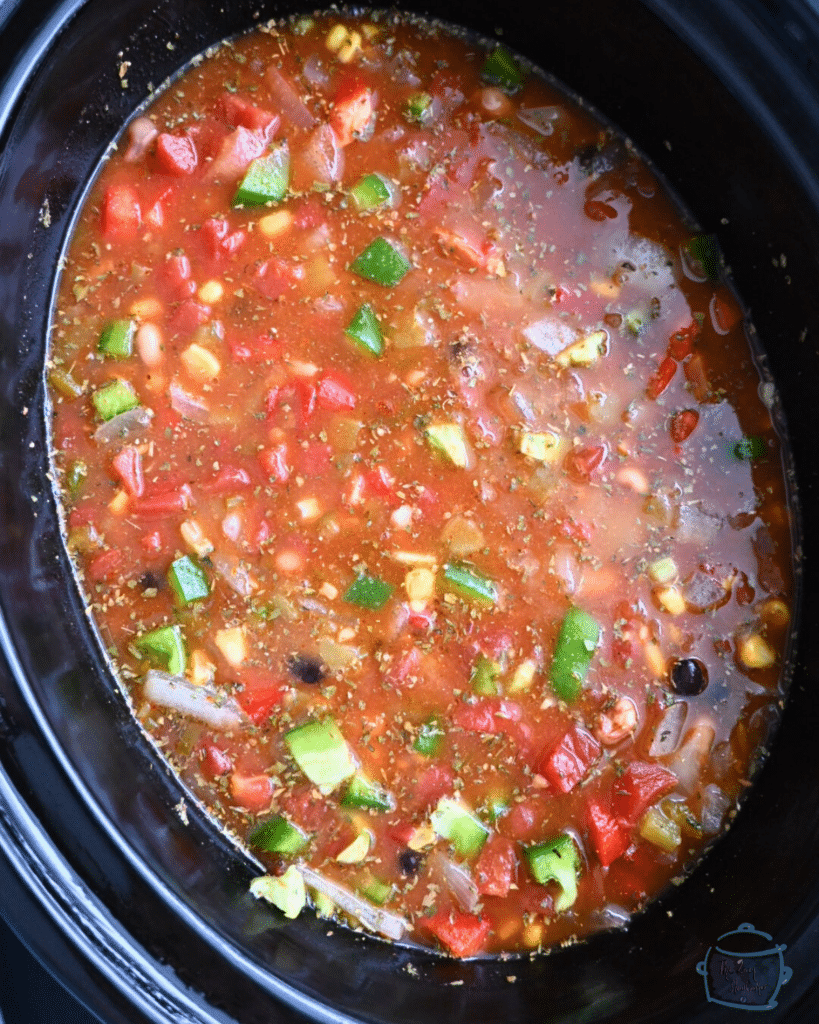 a crockpot full of cowboy caviar soup ingredients before cooking