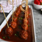 Guinness glazed meatballs on a tray with decorative picks for appetizers
